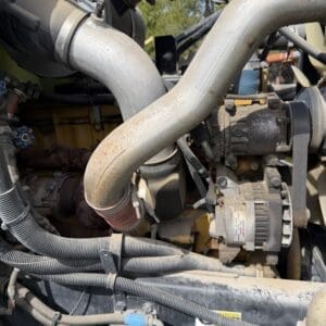 IMG_6920 - Montana Auctions by Kevin Hill Close-up of a diesel engine showing large curved metal intake/exhaust pipe, hoses, and an alternator belt area