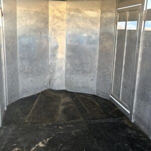 Screenshot - Montana Auctions by Kevin Hill Empty aluminum trailer interior with curved metal walls and vertical seams, and a dark scuffed floor; a metal door is visible on the right side.