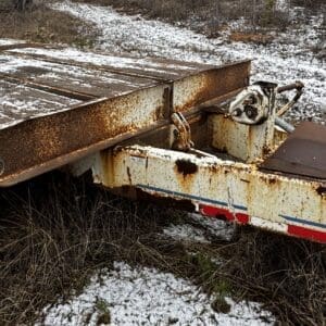 Rusty abandoned flatbed trailer lying in a snow-dusted field.