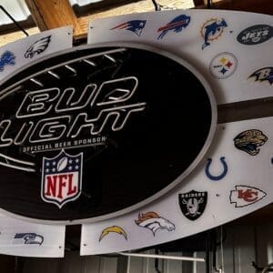 Oval Bud Light NFL sponsor sign with many team logos around the edge, mounted in a wooden structure.