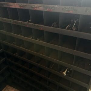 Metal tool organizer with a grid of empty cubby slots and a few tools resting in some compartments.