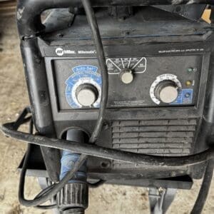 Front view of a Miller welding machine with Auto-Set dial, voltage and wire speed knobs and cables wrapped around the unit.