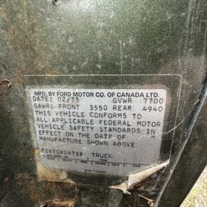 Close-up of a vehicle data plate on a green Ford truck, showing manufacturer and weight specs.