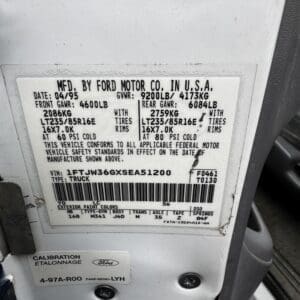 Informational vehicle ID plate on a white truck door showing GVWR, GAWR, tire sizes, rims, and VIN.