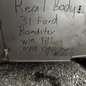 Handwritten sign on a metal panel advertising a real body 1931 Ford Roadster and asking for offers.