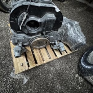 Used car heater blower assembly on a wooden pallet outdoors, with the circular fan housing and pulley visible.