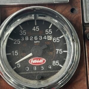 Close-up of a vintage car speedometer on a wood-grain dashboard, odometer showing 3,826,342 miles.