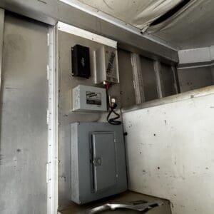 Industrial electrical panel and power switch mounted on a metal wall in a dusty utility room