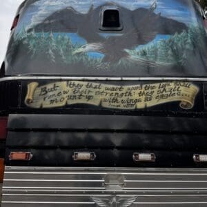 Rear of a black bus featuring an eagle mural over mountains and a scroll with Isaiah 40:31 text: 'But they that wait upon the Lord...'