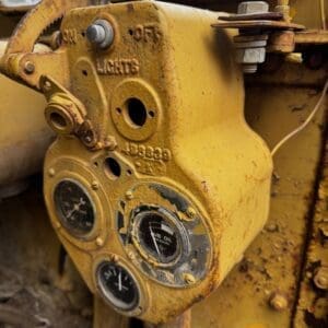 Close-up of a yellow, rusted industrial control panel with three round gauges and a lever, showing labels like 'LUB OIL' and 'PRESSURE'