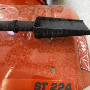Close-up of a black plastic chute/deflector attached to a red ST 224 snow blower or mower, seen from above.