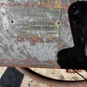 Rusted metal plate on an old New Holland machine showing serial 11490 and model 55.