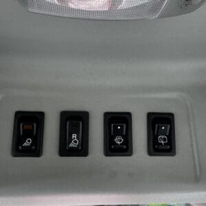 Overhead console in a vehicle with four switches: a dome/map light on the left, a labeled switch (R) for a light, and two windshield wiper/washer controls on the right.