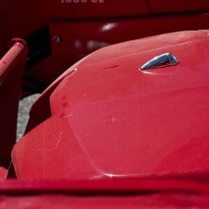 Close-up of a shiny red vintage car body with a chrome hood ornament and the numbers 1635 CL on a red panel