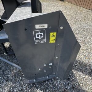 Ironcraft steel attachment with serial 303347 and safety warning labels on a gravel lot.
