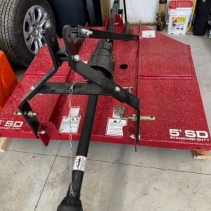 Red flatbed utility trailer with a black hitch assembly and safety chain in a garage setting.